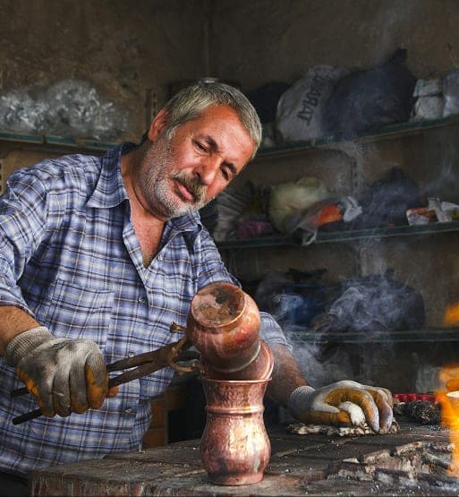 Artisan marocain travaillant une pièce de cuivre dans son atelier