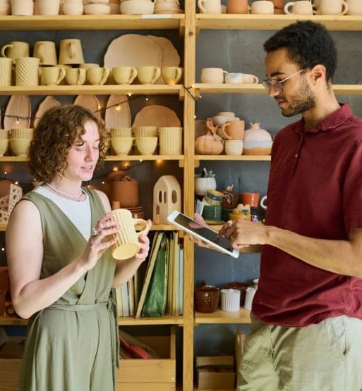 Deux personnes vérifiant une pièce de poterie dans un atelier