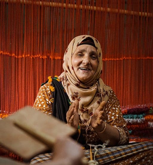 Artisane souriante travaillant devant des fils de tissage colorés